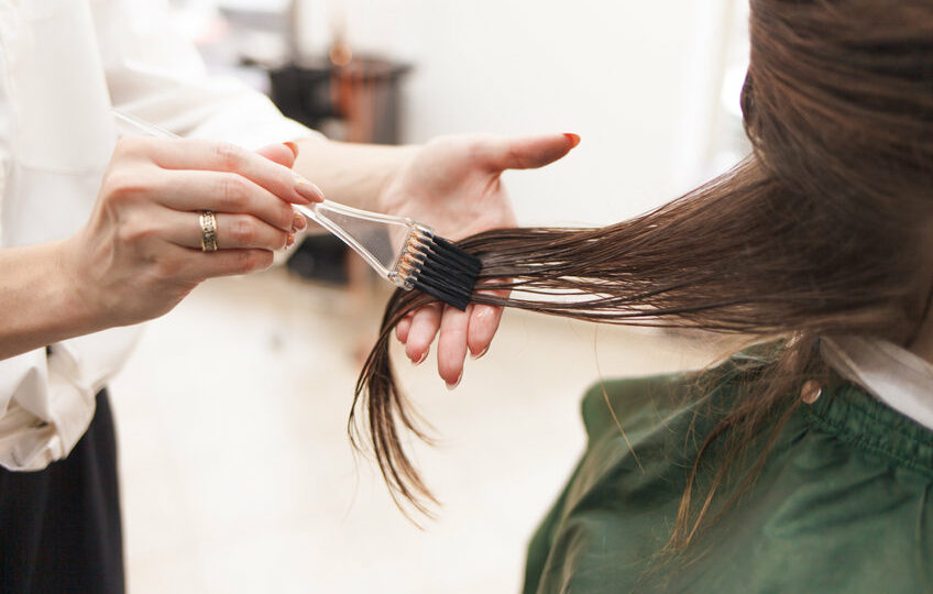 hairdresser applies a hair mask to the woman in the beauty salon. botox and keratin hair straightening procedure