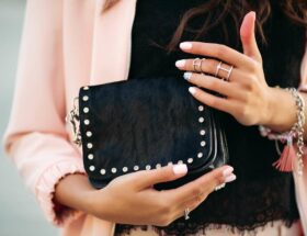 mains feminines avec un beau vernis a ongles et des anneaux tenant un petit sac noir 11zon